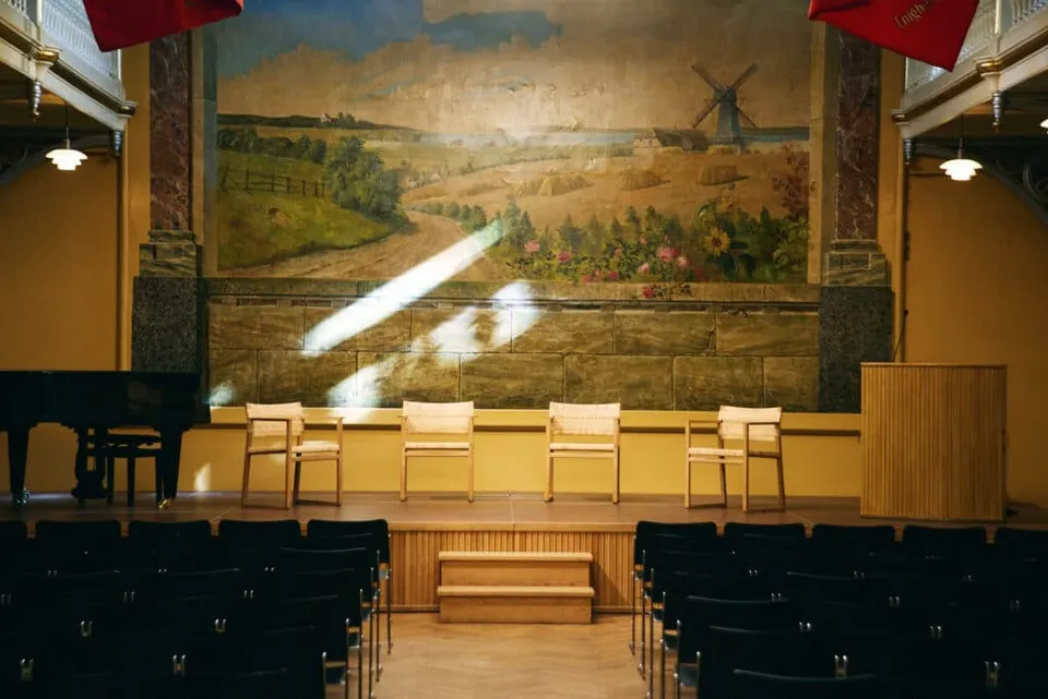 Arbejdermuseets Festsal med scene, vægmaleri og røde bannere.