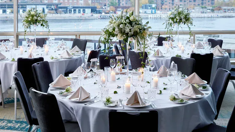 Copenhagen Marriotts selskabsopstilling med runde middagsborde ved havnevinduerne.