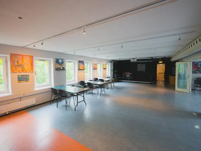Caféen i Støberiet med caféborde, store vinduer og kunst på væggene.