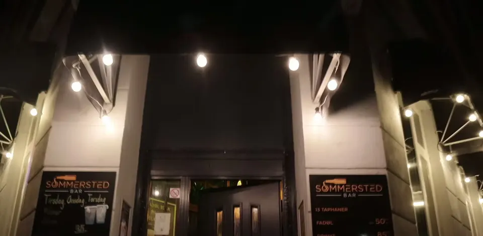Café Sommersteds oplyste facade og indgang ved aftentid.