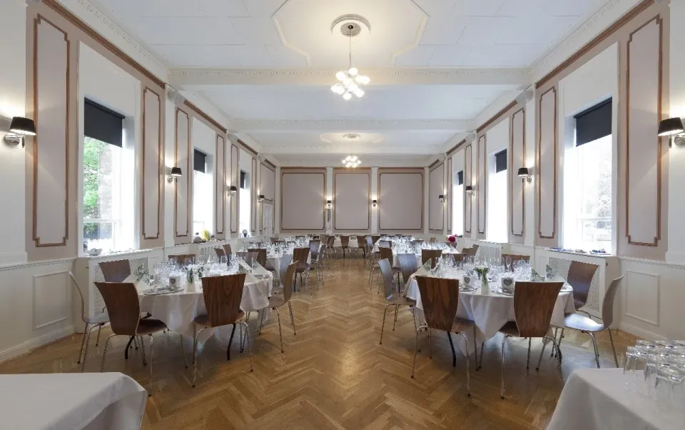Den Gamle Dansesal med runde opdækkede borde og parketgulv.