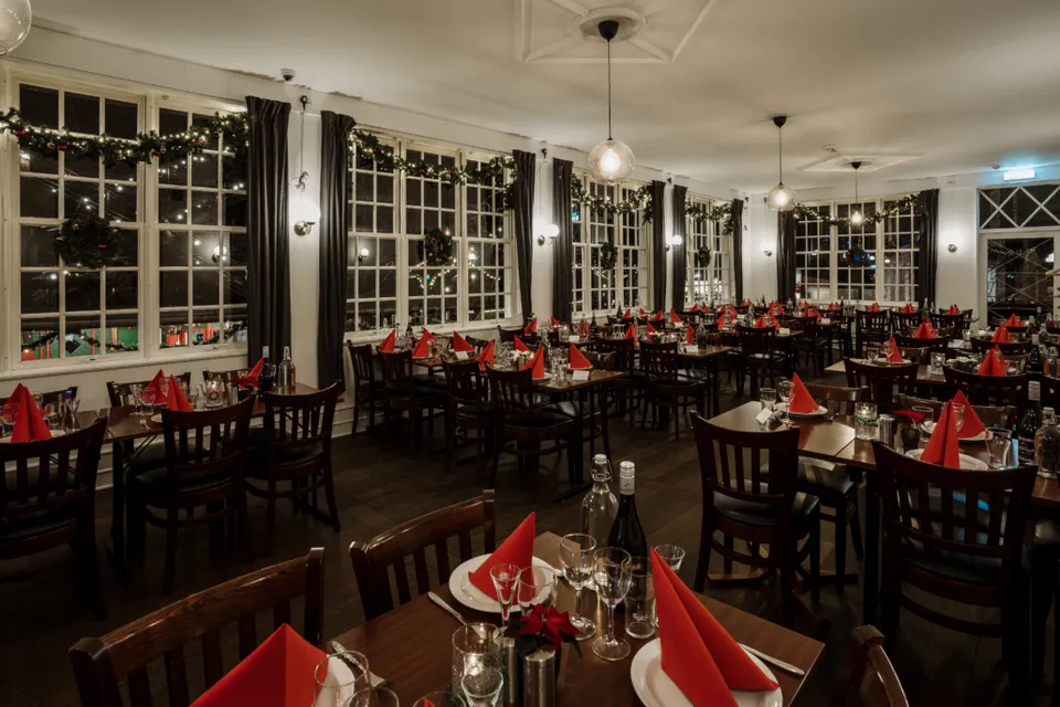 Restaurant Bakkens Perle: Restaurant med dækkede borde, røde servietter og store sprossevinduer.