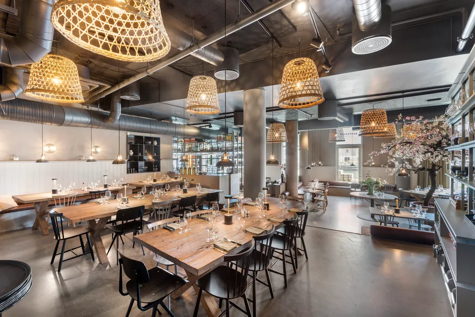 Boathouse: Restaurantlokale med lange træborde, stole og store hængelamper.