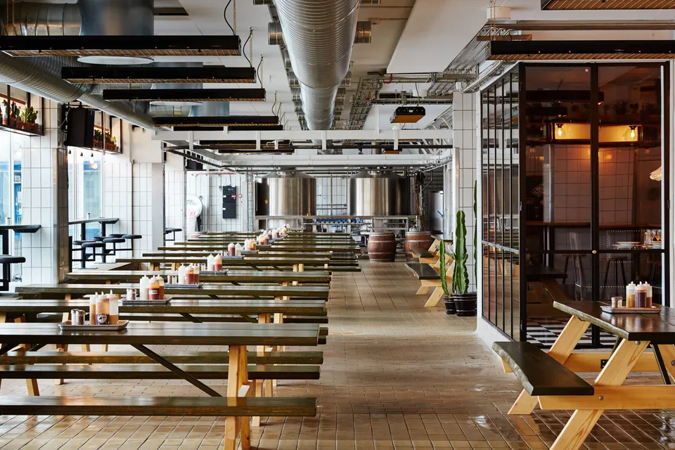Warpigs Brewpub: Brewpubbens store rum med lange bænke, borde, rør og bardisk.