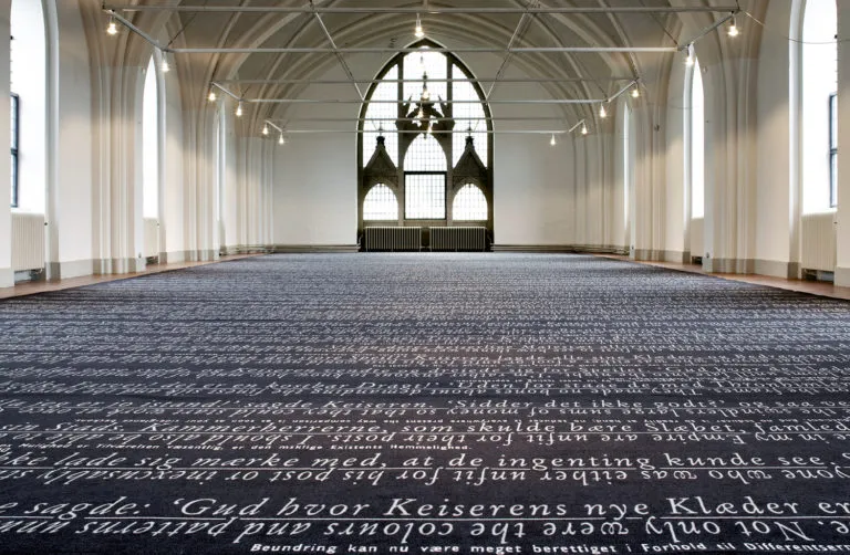 Øvre Galleri v. Nikolaj Kunsthal: Galleri med spidsbuede vinduer, hvælvet loft og skrift på gulvet.