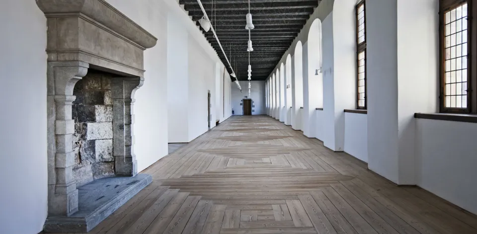 Det Blå Galleri v. Kronborg: Langt galleri med trægulv, vinduesrække og en stor stenpejs.