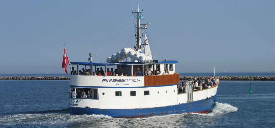M/S Langø v. Spar Shipping: Hvidt passagerskib med træoverbygning og gæster på dækket på åbent vand.