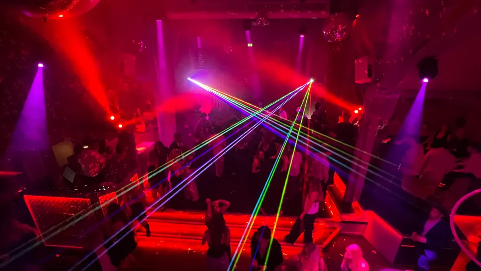 Reservatet v. Skovriderkroen: Reservatets dansegulv og trapper med gæster under farvede lys og laserlys.