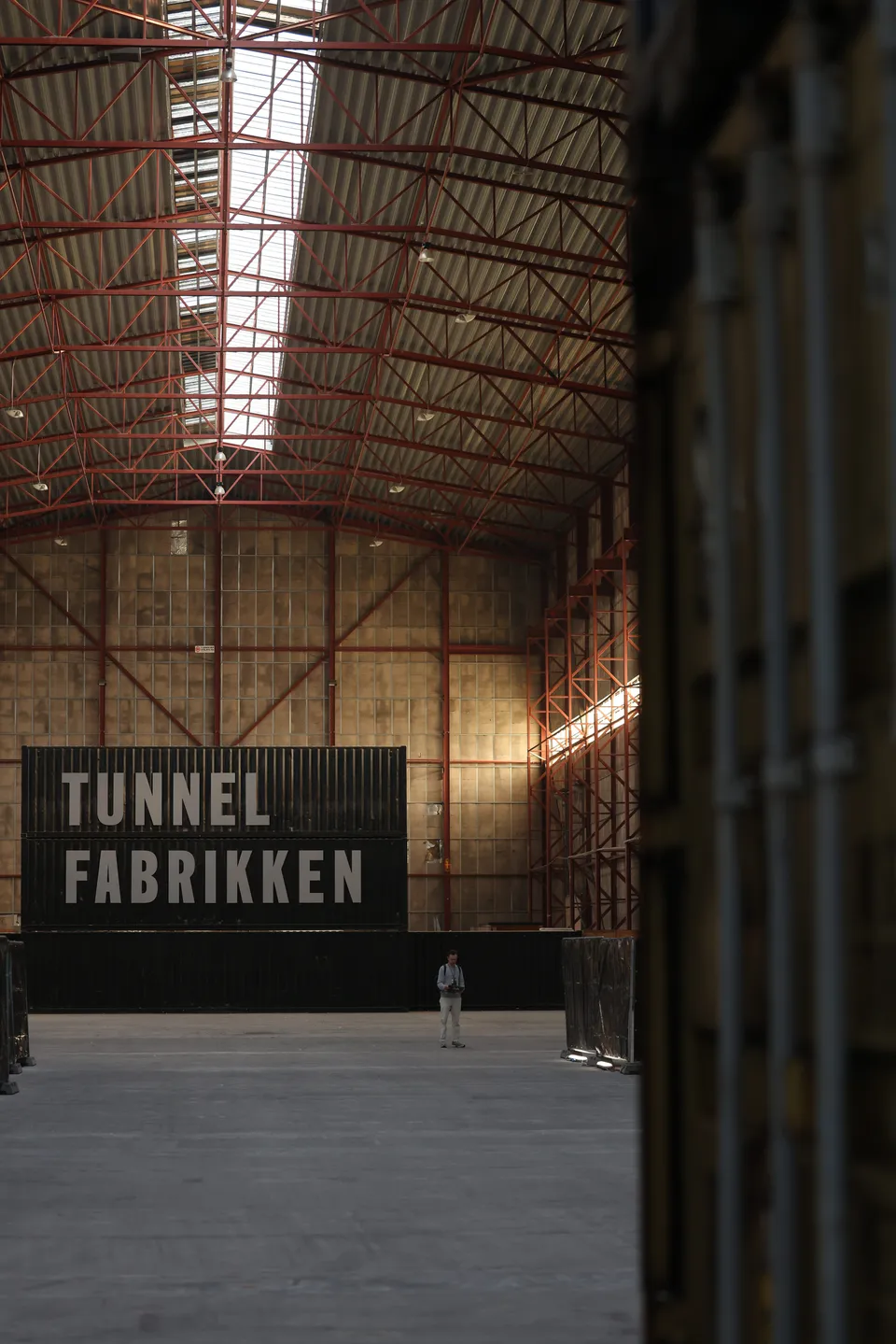Tunnelfabrikken / Odds and Ends: Langt industrirum med høje stålkonstruktioner, ovenlys og et stort åbent gulvareal.