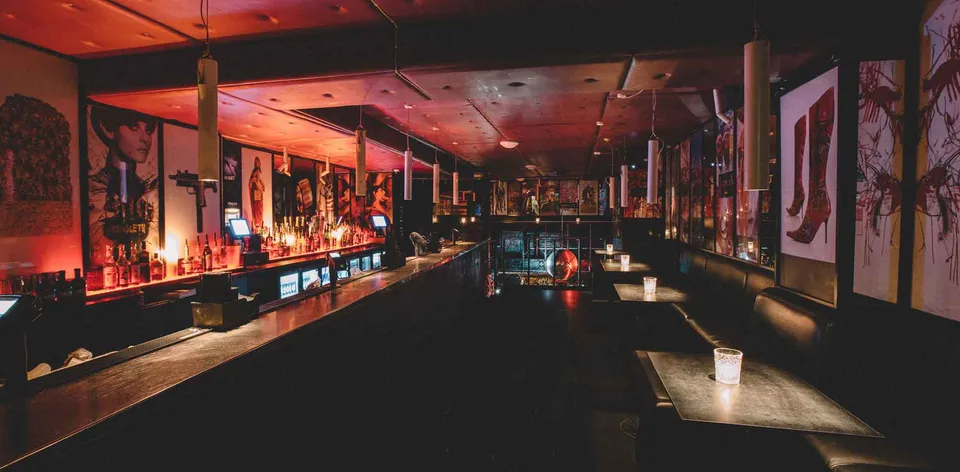 The Gallery v. Hornsleth Bar: Lang bar med siddepladser, vægkunst og varm belysning.