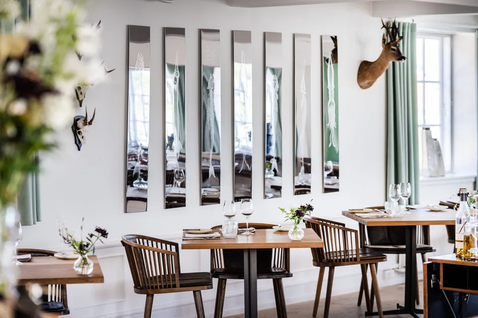 Restaurant Njörðr v. Hotel Siemsens Gaard: restaurantborde og træstole i et lyst rum med smalle vægspejle.