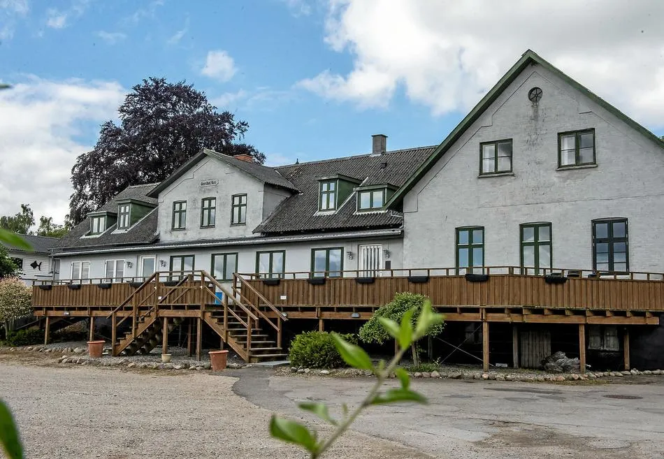 Dronningesalen v. Gershøj Kro: Lys krobygning med gavle og en træterrasse langs facaden.