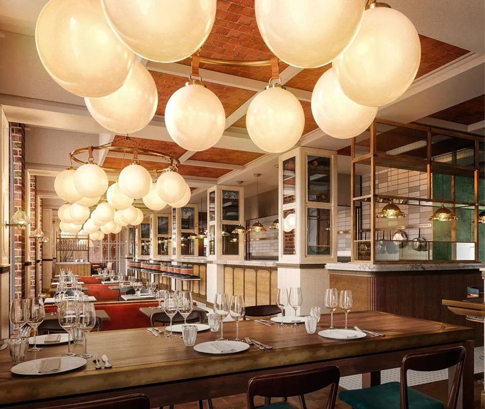 Brasserie Kontrast v. Villa Copenhagen: Restaurant med mange træborde, lyse skillevægge og store runde pendler.