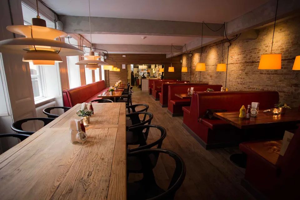 Cocks & Cows Gammel Strand: Langt restaurantlokale med træbord, høje stole og røde bænke.