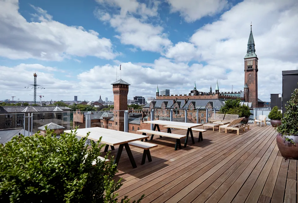 Tagterrassen v. Hotel Danmark: Tagterrasse med træbænke, borde og udsyn over byens tage og tårne.
