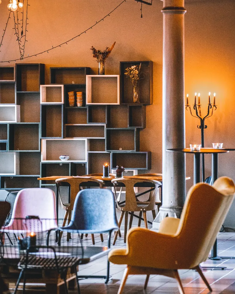 Food Space v. Kødbyen: Loungeområde med farvede stole, sofa og reoler.