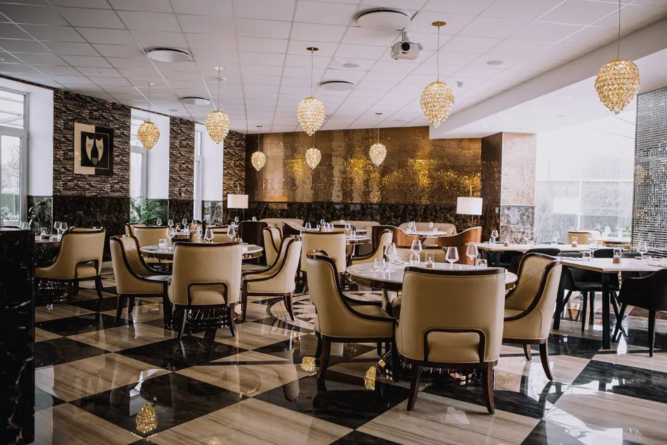 Bovi Bar & Grill: Restaurant med lyse lænestole, dækkede borde og sort-hvidt flisegulv.