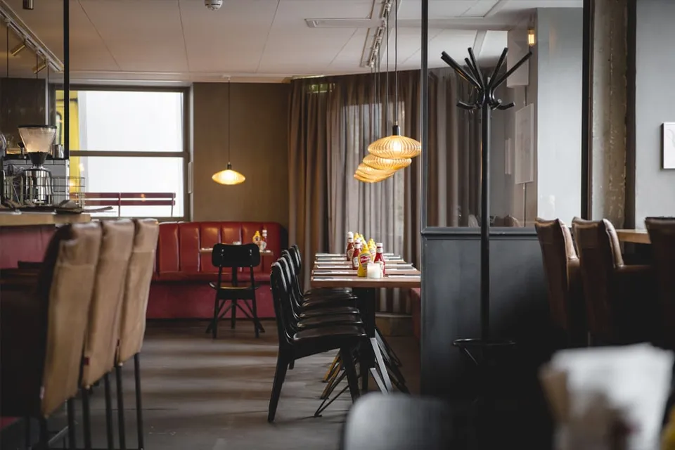 Cocks & Cows SP34: Restaurantens siddeområde med borde, stole og vinduer.