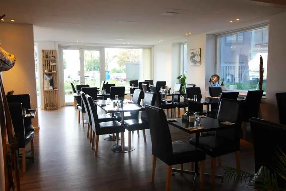 Restauranten v. Couloir: Restaurantlokale med sorte stole, borde og brede vinduer.