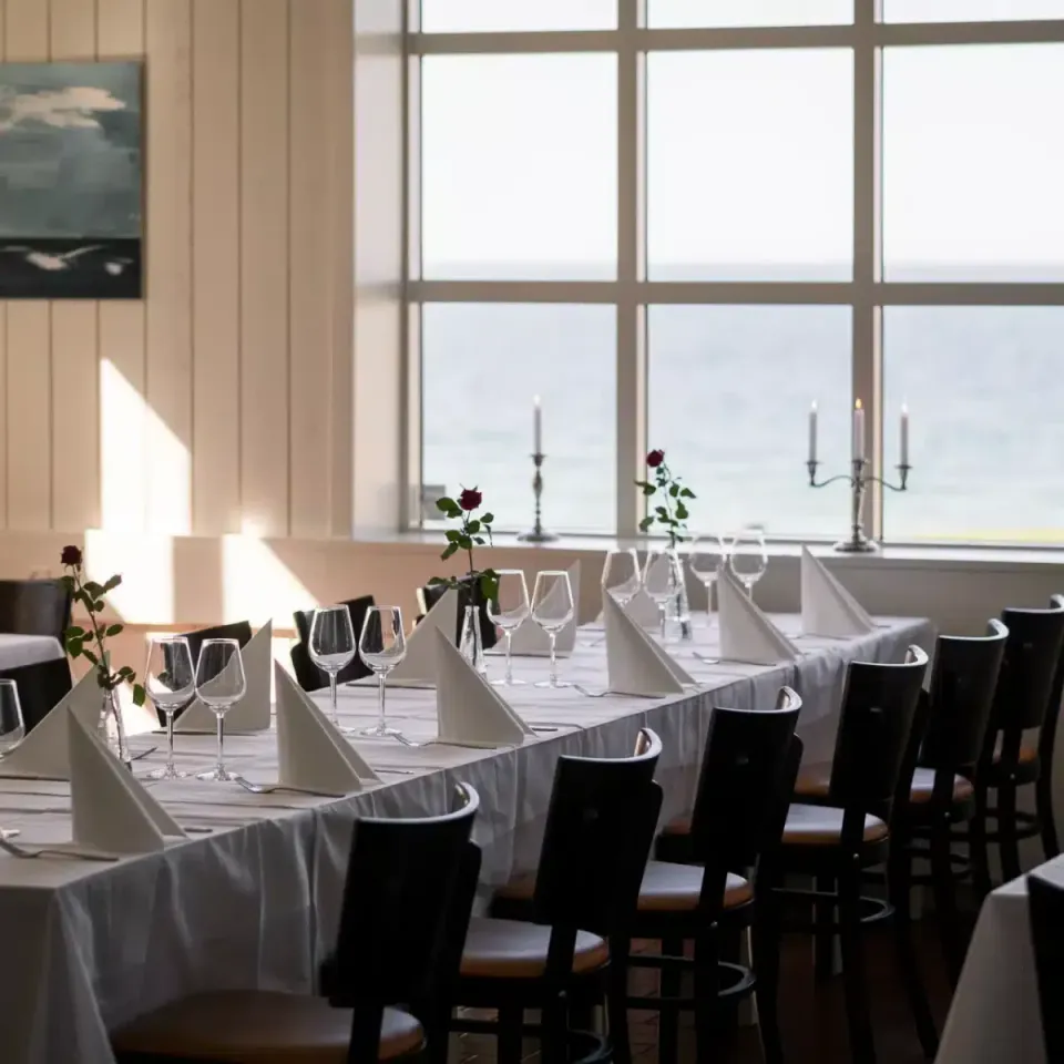 Festsalen v. Gilbjerg Strandhotel: dækkede langborde med hvide duge foran store vinduer.