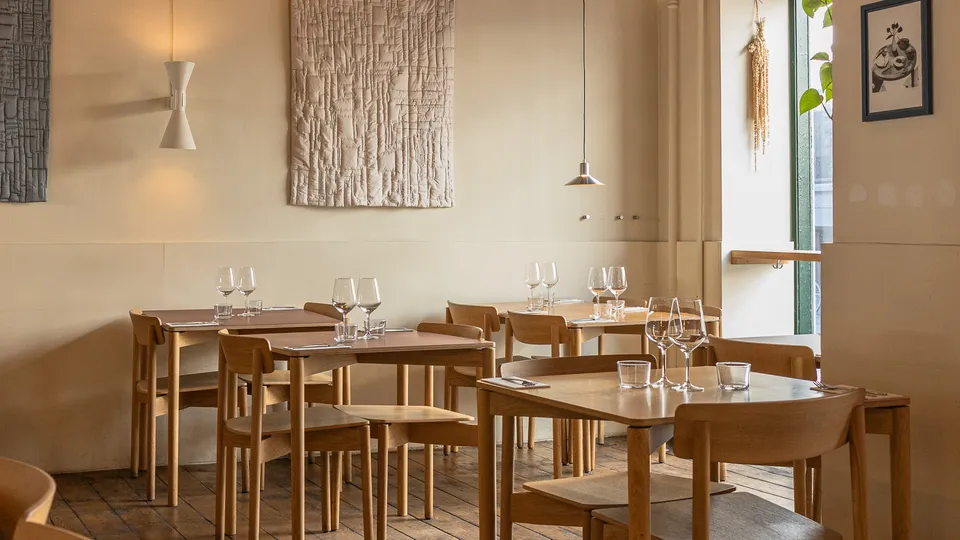 THEO: små borde og træstole i et lyst restaurantlokale med vægtekstiler.