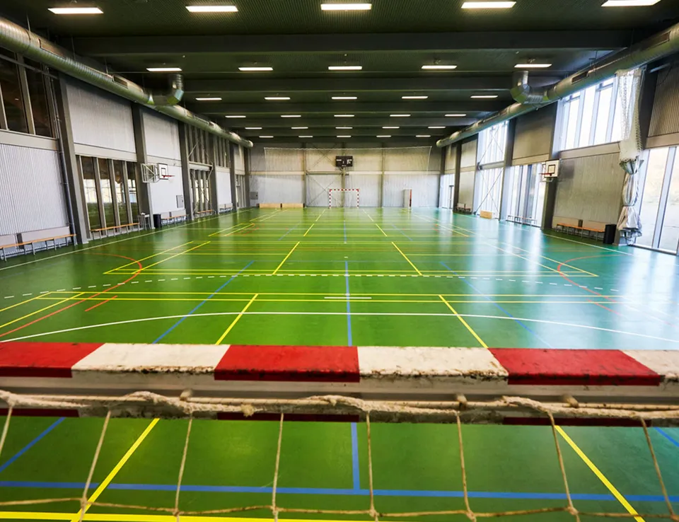 Multihallen v. Hafnia Hallen: Idrætshal med grønne baner, høje vinduer og en bom på tværs af forgrunden.