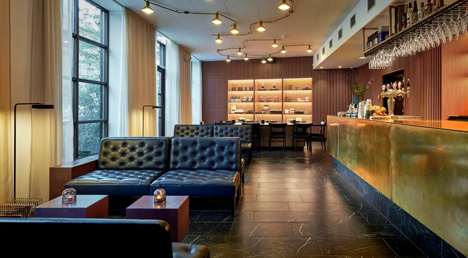 Hotel Danmark: Hotellounge med blå sofaer og en lang barskranke ved høje vinduer.