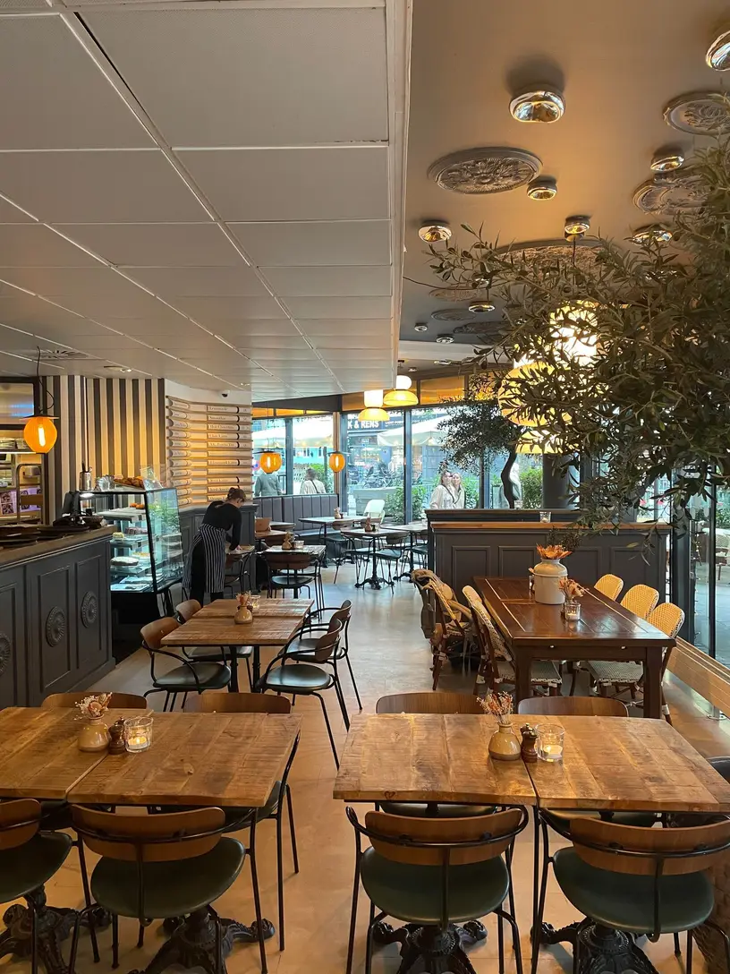 Mojoe Kitchen & Bar: Langt restaurantlokale med træborde, blandede stole og planter.