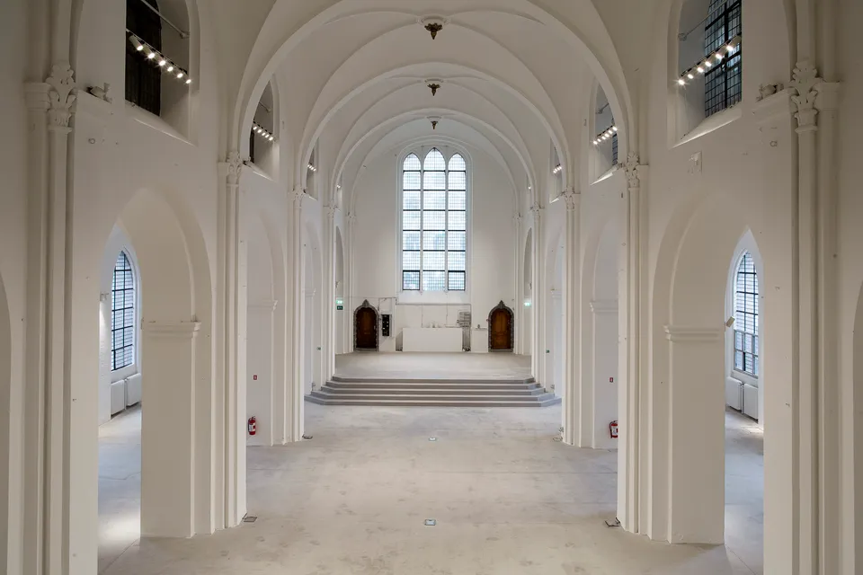 Nedre Galleri v. Nikolaj Kunsthal: Lyst galleri med høje søjler, hvælvinger og buede vinduer.