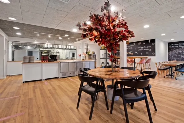 Restaurant Staldknægten: Lyst restaurantlokale med runde borde, træstole og en åben serveringsdisk.