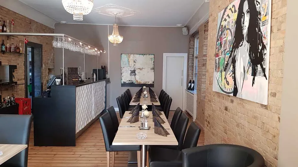 Galleriet v. Restaurant Upstairs: Langt lokale med træborde, sortpolstrede stole, bar og murstensvæg.