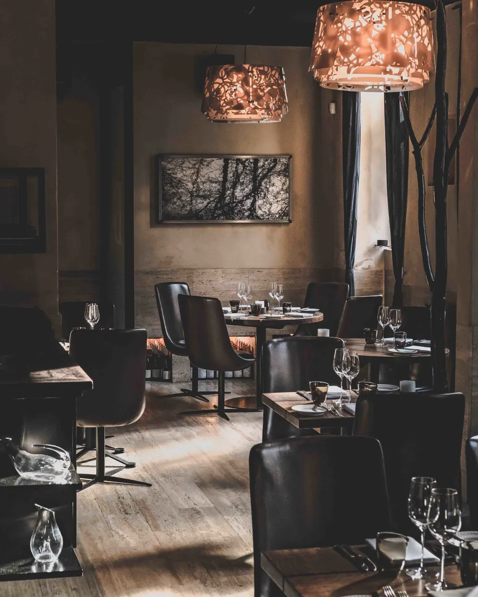 Formel B: restaurantområde med dækkede borde og store pendellamper i dæmpet lys.