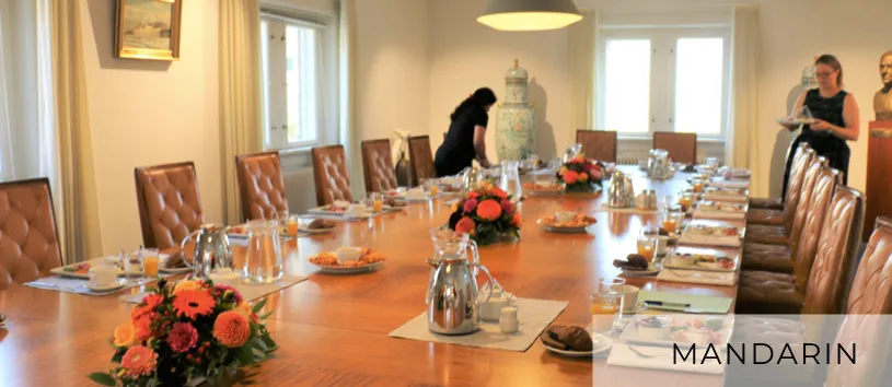 Mandarin v. Eventspace Asia House: Dækket langbord med brune læderstole og enkelte personer i baggrunden.