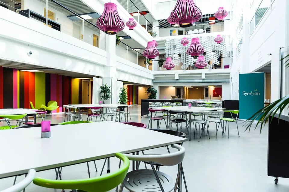 Restauranten v. Symbion Konferencecenter: Lyst atrium med borde, grønne stole og farverige hængelamper.