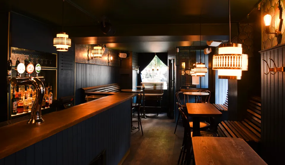 The Flatiron Speakeasy: Lang bar med ølhaner, små borde og mørke vægpaneler.