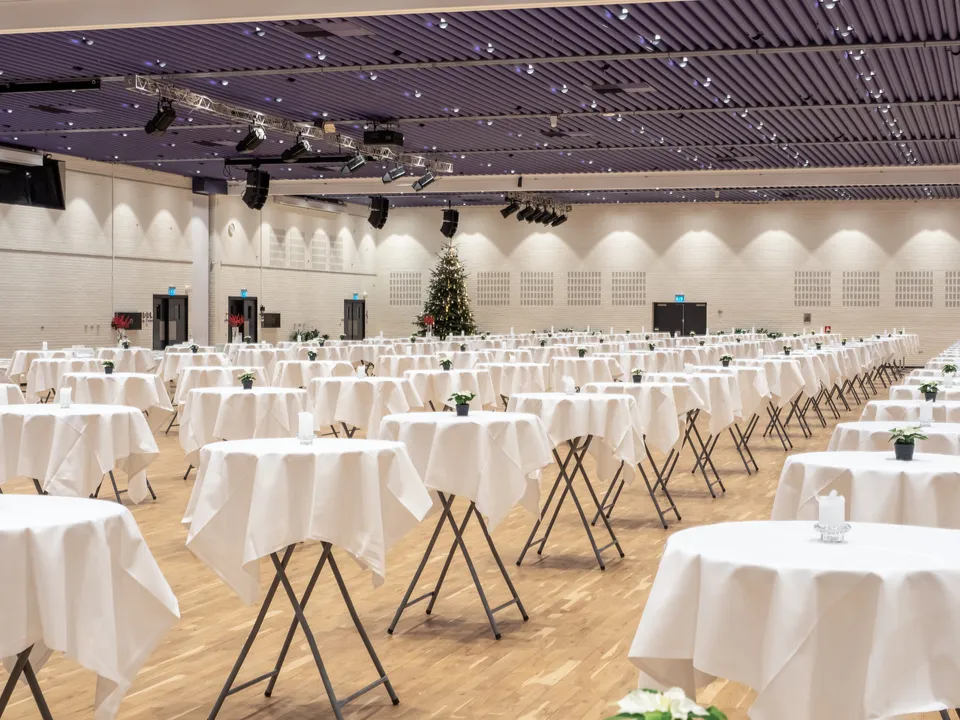 Danmark Salen v. Odense Congress Center: høje borde med hvide duge fordelt i en stor sal med lilla loft.