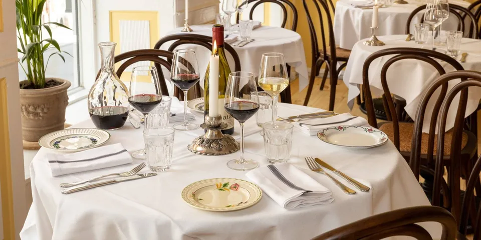 Restaurant Gabrielle: Dækkede runde borde med hvide duge og mørke bøjettræsstole i et gult restaurantlokale.