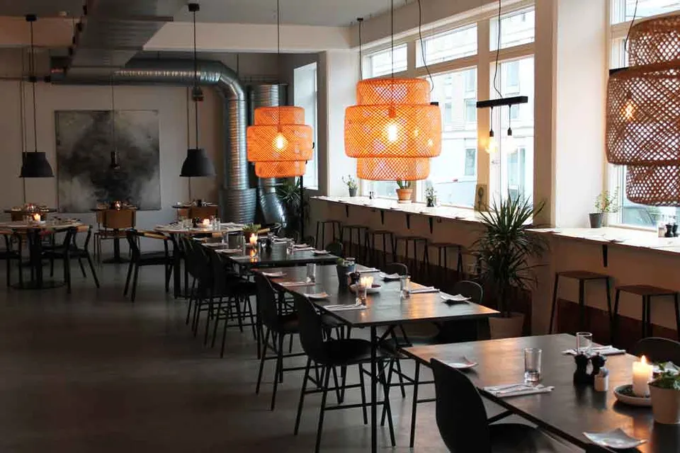 Bistro Couloir v. CPH Studio Hotel: Spiseområdet med borde, stole, vinduer og pendellamper.