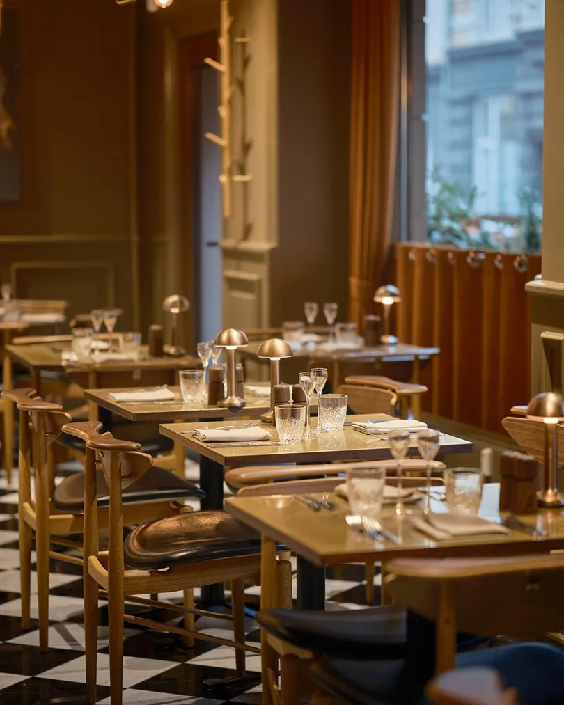 Restaurant Palægade: dækkede restaurantborde, træstole og polstrede bænke langs vinduer.