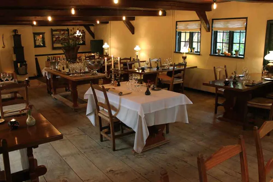 Restauranten v. Sortebro Kro: Dækkede borde i et restaurantlokale med træbjælker og varme vægfarver.