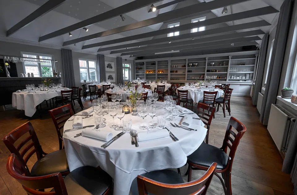 Annekset v. Restaurant Kanalen: Runde dækkede borde og træstole foran en lang reolvæg i et lyst lokale.