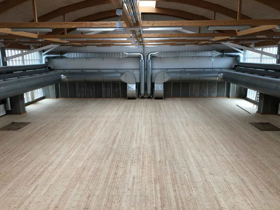 Eventlokalet v. Copenhagen Contemporary: Stort åbent lokale med trægulv, synlige bjælker og ventilationsrør.