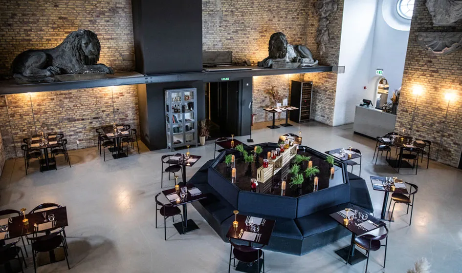 Tårnet v. Christiansborg Slot: højt restaurantområde med murstensvægge, skulpturer og borde omkring en central bar.