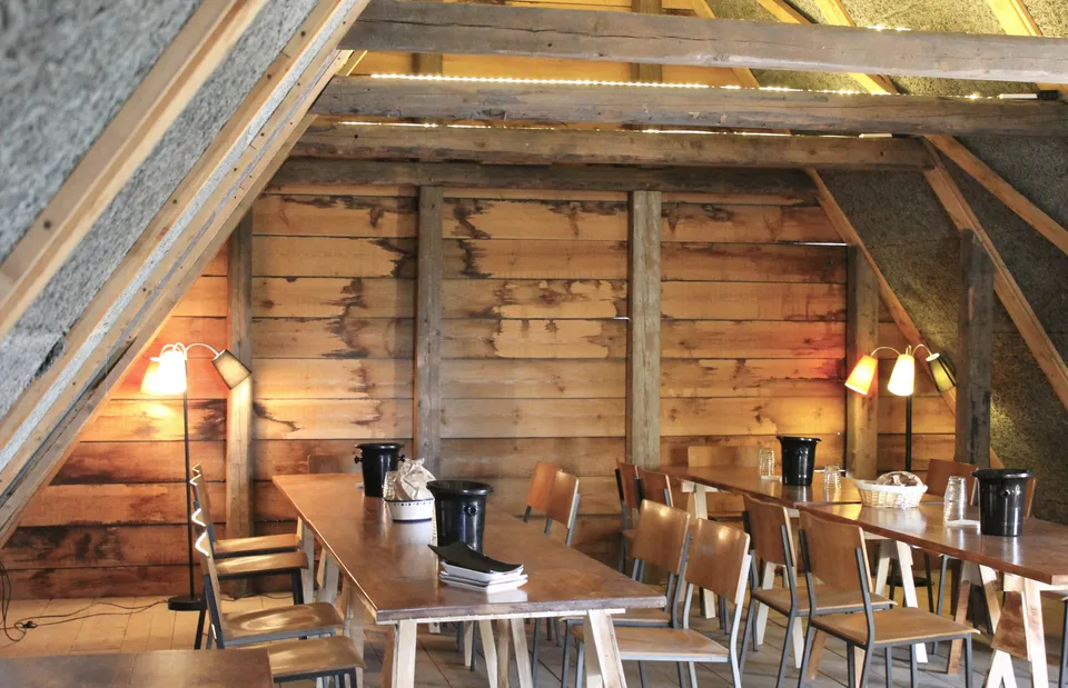 Hestestalden v. Store Godthaab: Træborde og stole under et skråt loft med synlige træbjælker.