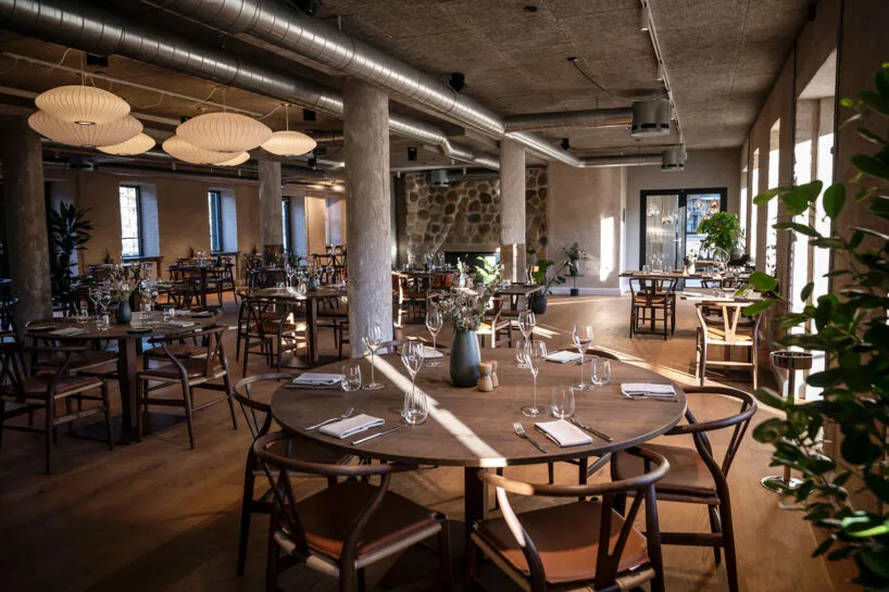 Restaurant Herkomst: Restaurant med runde træborde, betonsøjler, planter og rå stenpartier.