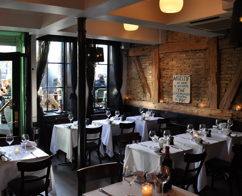 Heering Restaurant & Bistro: Dækkede borde i en restaurant med murstensvæg og store vinduer.