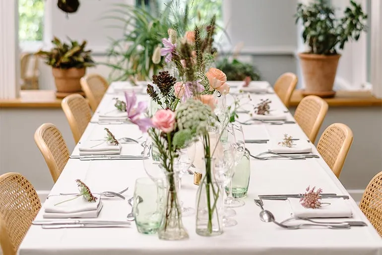 Restaurant Kilden v. Tivoli: Langt dækket bord med stole og vinduer i baggrunden.