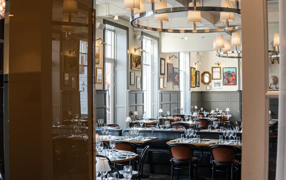 Brdr. Price Herning: restaurantområde med dækkede borde, loftslamper og indrammede billeder.