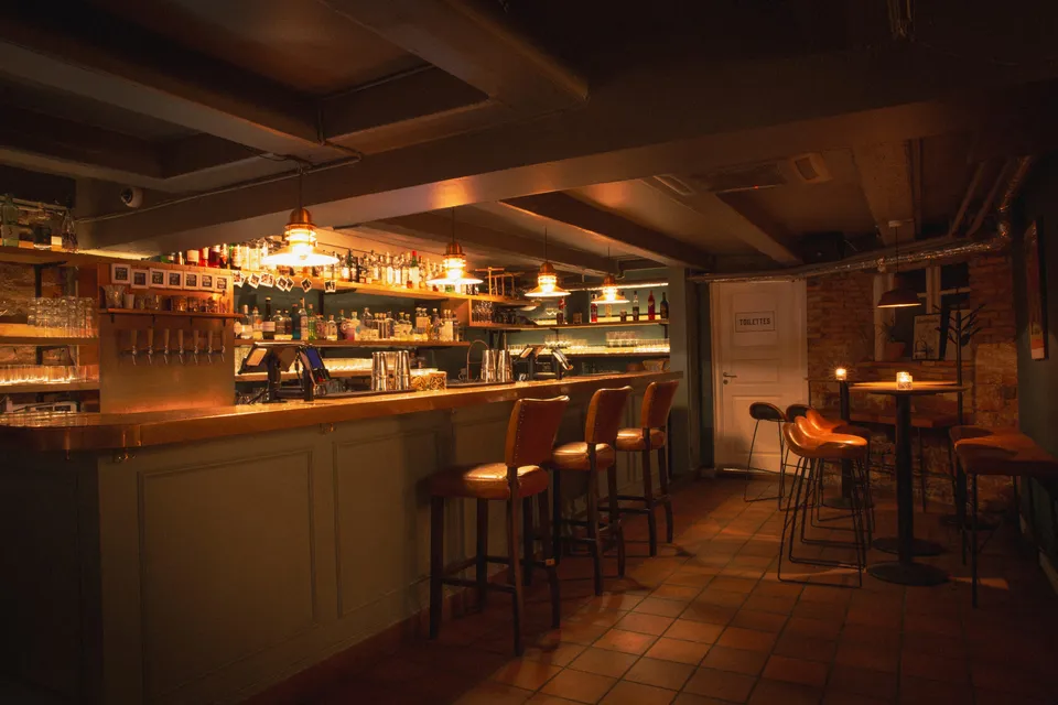 The Bird & The Churchkey: Den træbeklædte bar med bardisk, barstole og ophængte lys.